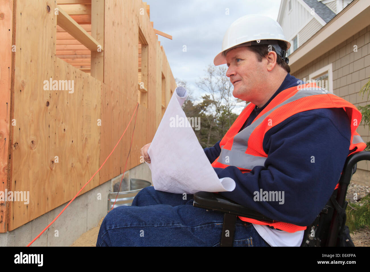 Construction engineer with spinal cord injury holding house plans at ...