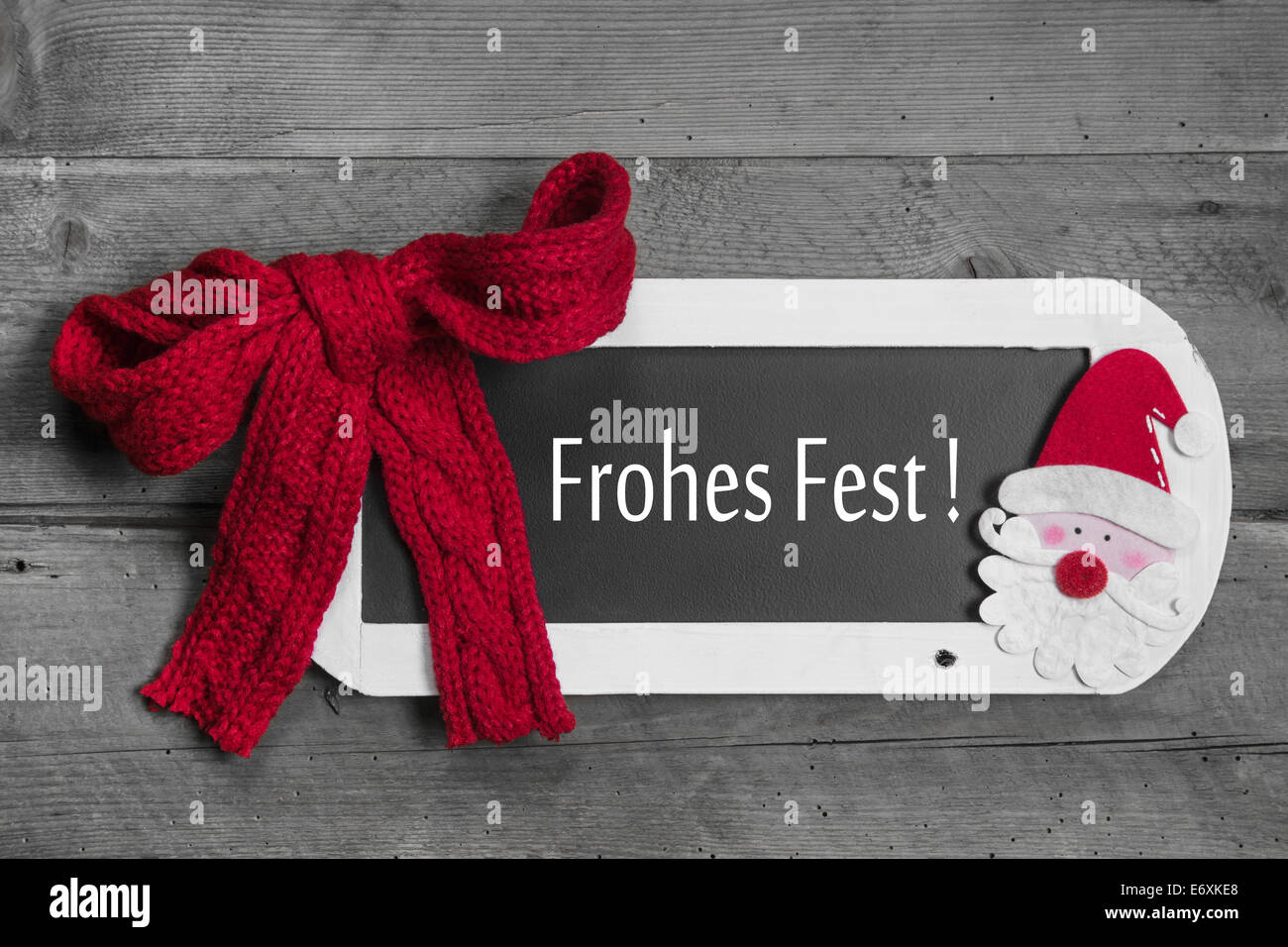 Red bow on menu board with Merry Christmas - Frohes Fest - german message on wooden background Stock Photo