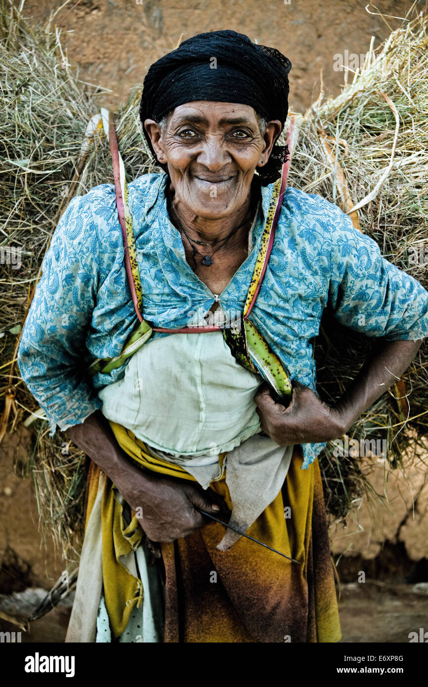 Old woman from the Dorze tribe carrying a bundle of hay, South Ethiopia, Africa Stock Photo