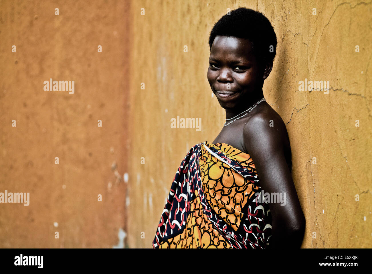 Young woman in traditional Kanga in front of a yellow wall, Uganda, Africa Stock Photo