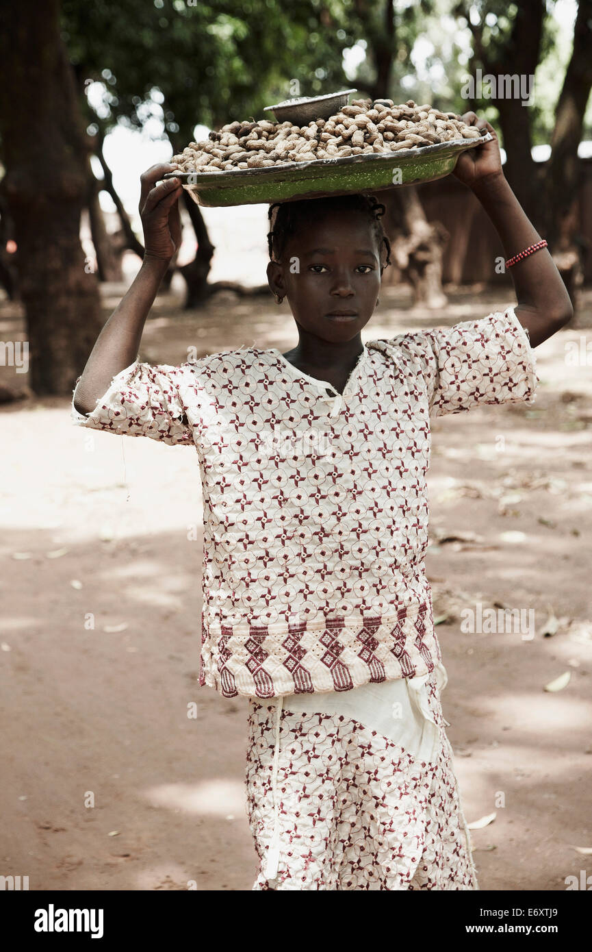 Girl carrying on head a tray with peanuts to market, Yanfolila, Sikasso Region, Mali Stock Photo