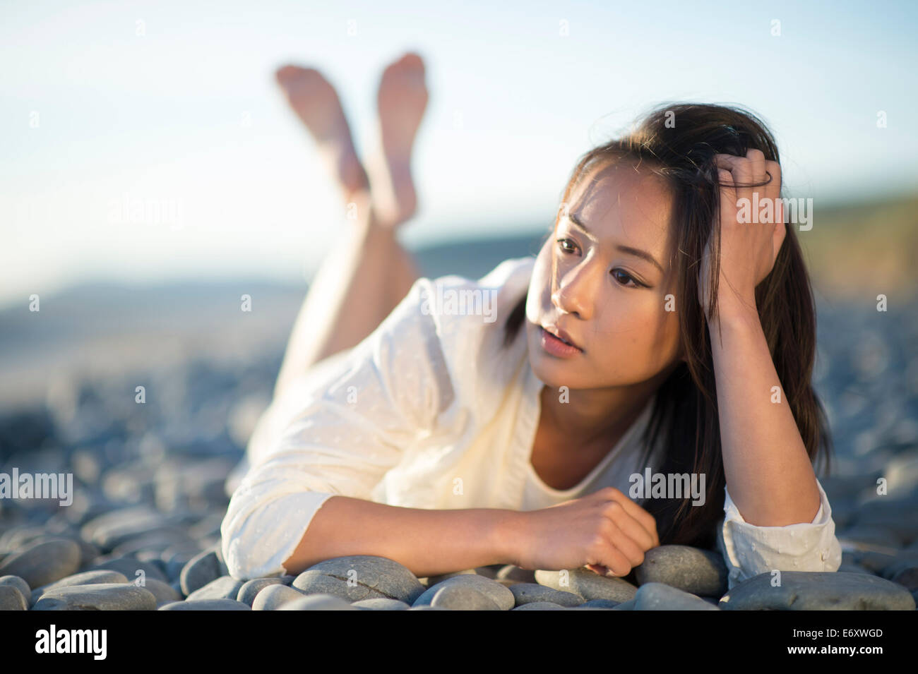 A young ethnic asian chinese  woman girl lying on ground looking thoughtful pensive sad low lonely single solo UK Stock Photo