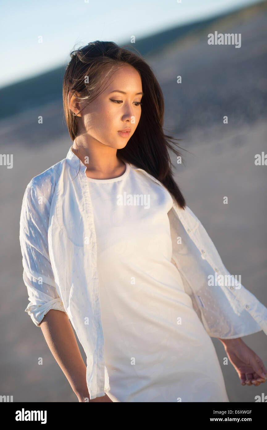 A young ethnic asian chinese  woman girl wearing white dress looking thoughtful pensive sad low lonely single solo UK Stock Photo