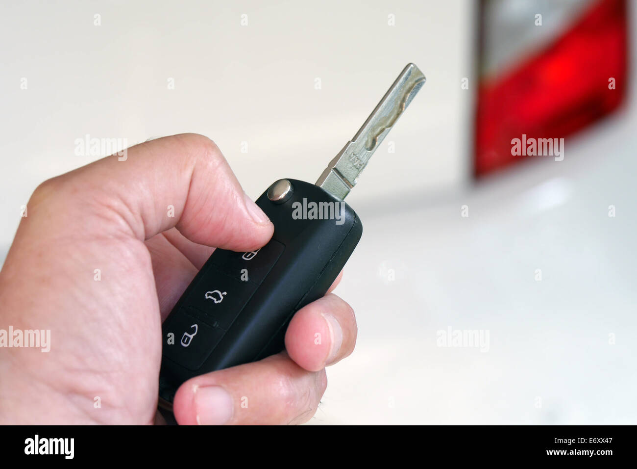 Man holding car key with white car in background Stock Photo