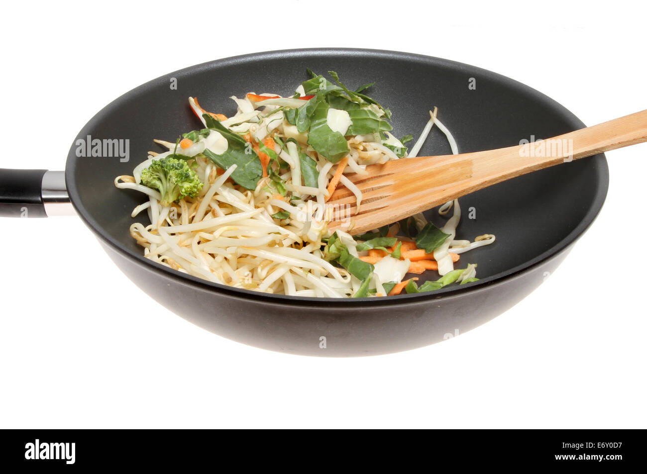 Closeup of a wok with stir fry vegetables, bean sprouts and a wooden spatula isolated against white Stock Photo