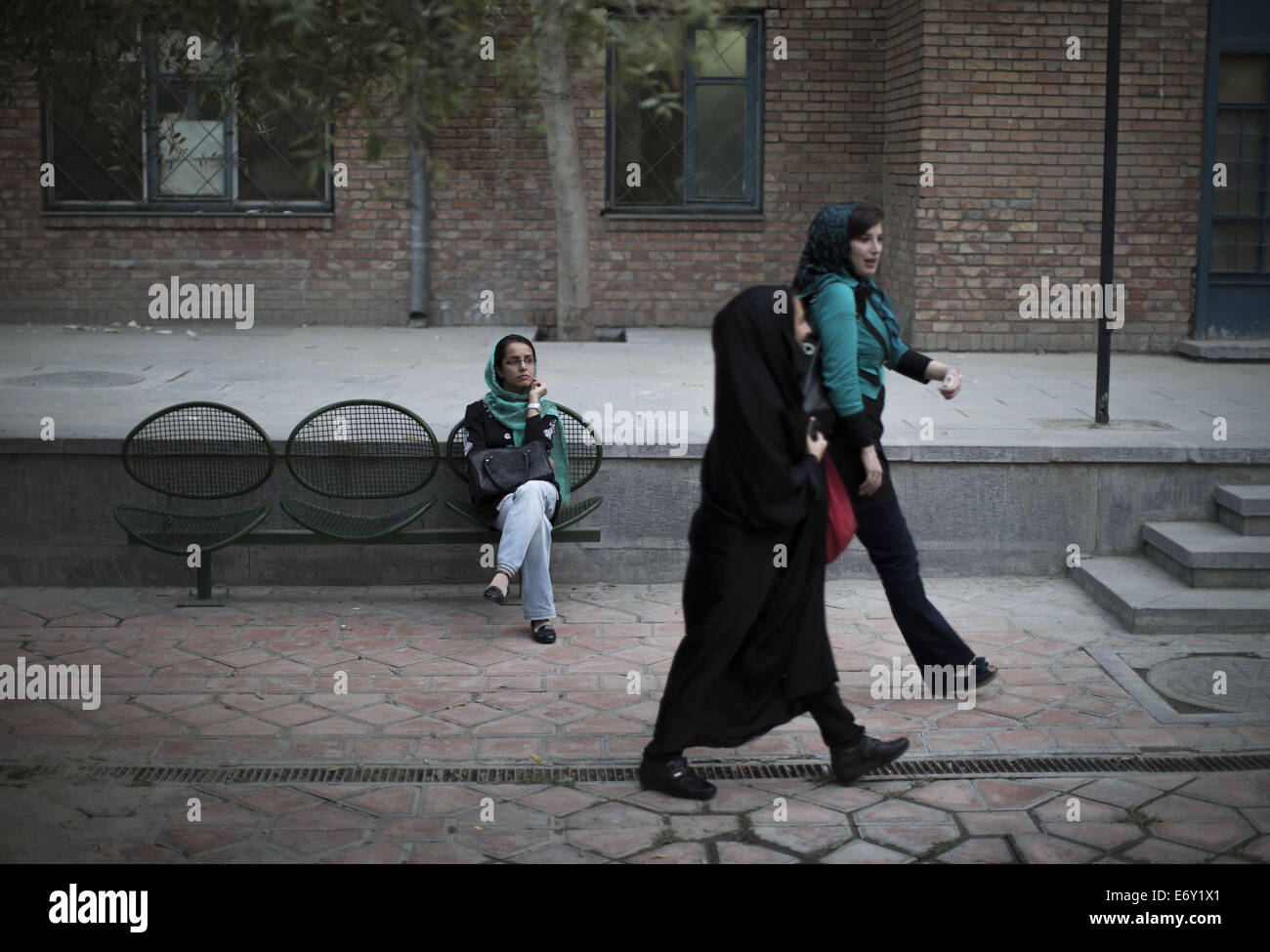 Tehran, Iran. 1st Sep, 2014. Two Iranian women walk past a woman who is rest out of the Iranian Artists' Forum in Tehran's Artists Park. Credit:  Morteza Nikoubazl/ZUMA Wire/Alamy Live News Stock Photo