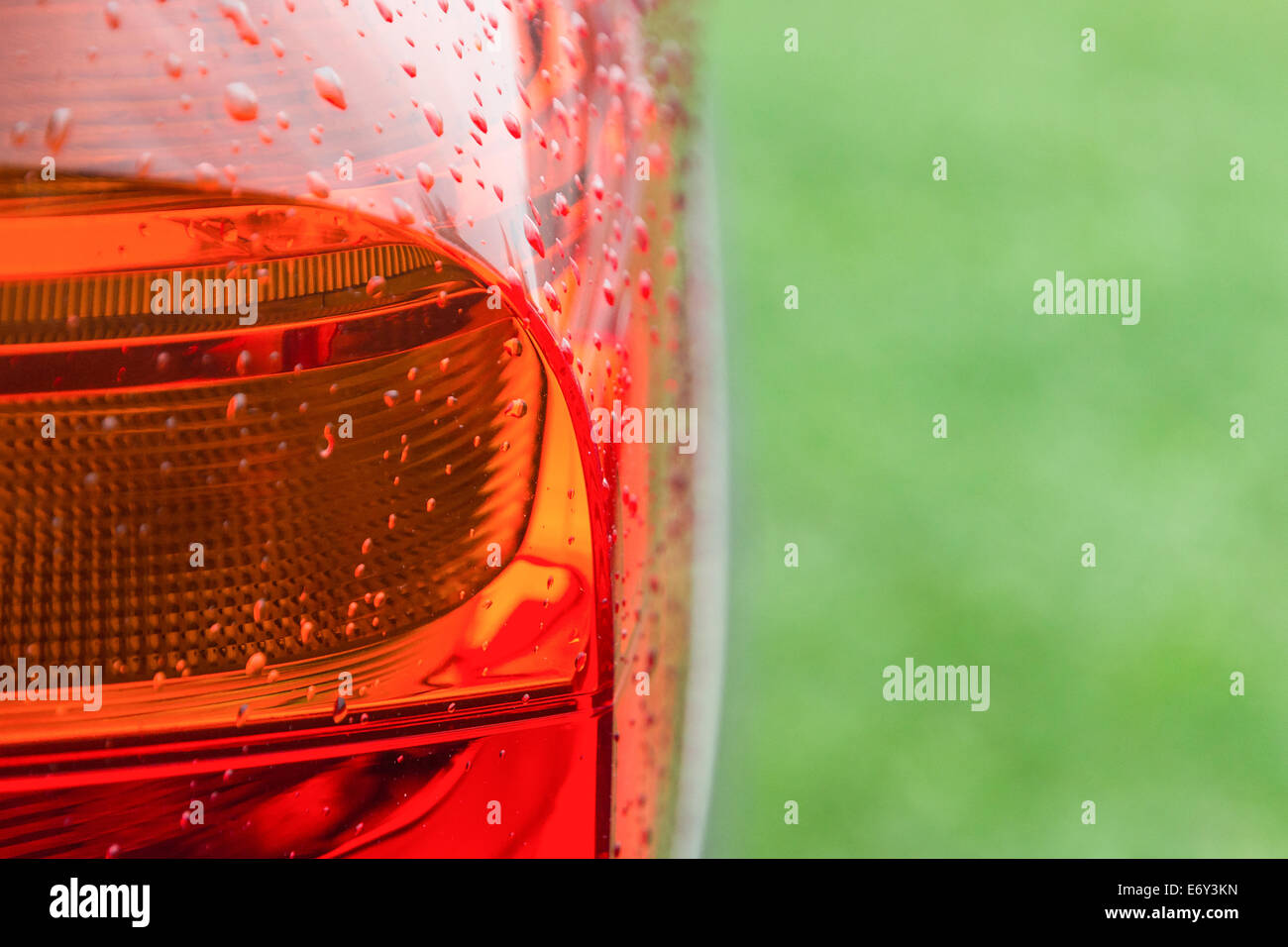 Wet after rain with water drops tail lights of new modern car on fresh