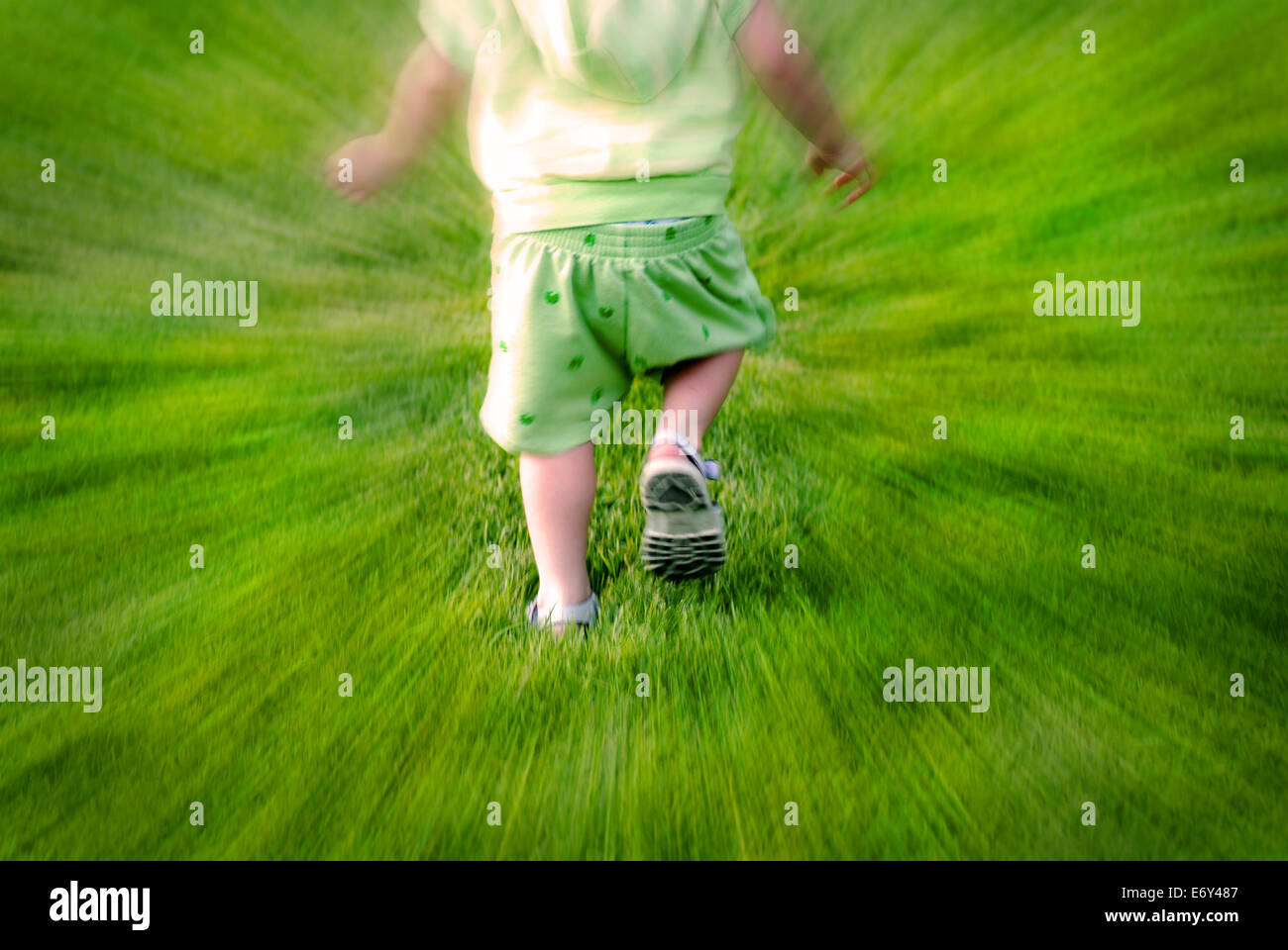 Zoomed shot of little child toddler running in grass having fun Stock Photo