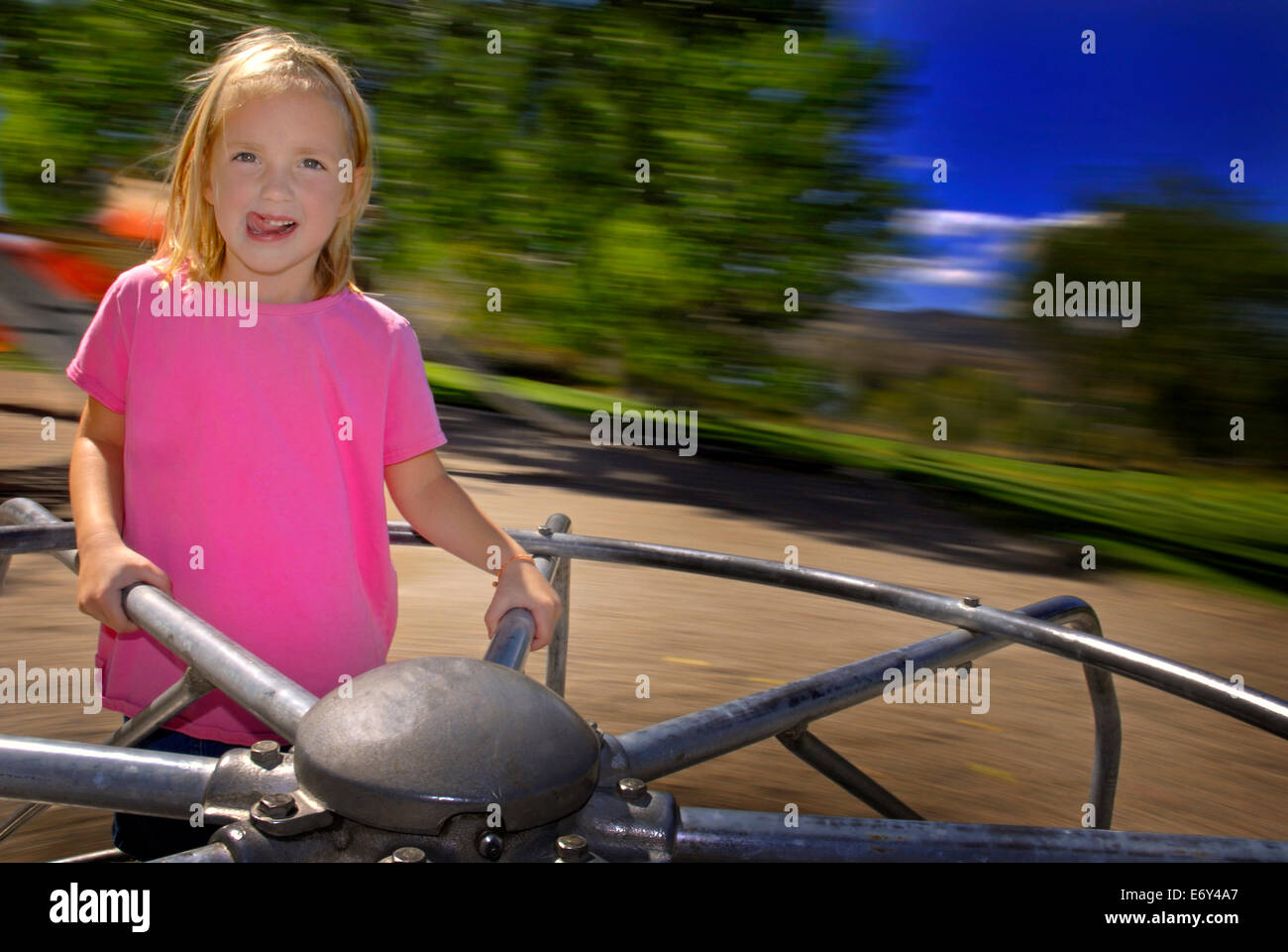 Little girl playing on merri-go-round at a park Stock Photo