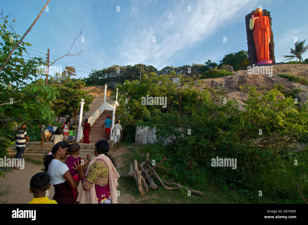 Sri Lankan visitors with small child beneath a buddhist statue near Kirinda, Southern Sri Lanka Stock Photo