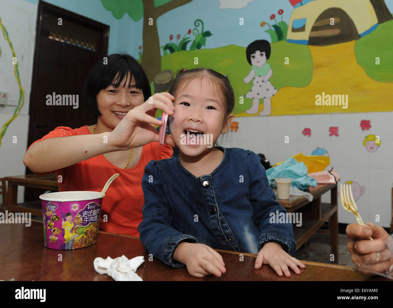 Chongqing, China's Chongqing Municipality. 2nd Sep, 2014. Four-year-old girl Hu Yuan (R) phones her father at a shelter after evacuating from rain-pounded township in Yunyang County, southwest China's Chongqing Municipality, Sept. 2, 2014. Eight people died and 24 others were missing as of early Tuesday after rainstorms brought landslides to Chongqing, said the local rescue headquarters. More than 500 professional rescuers have evacuated over 7,000 residents in nine rain-drenched townships in Yunyang County to safe locations, said the headquarters. Credit:  Chen Cheng/Xinhua/Alamy Live News Stock Photo