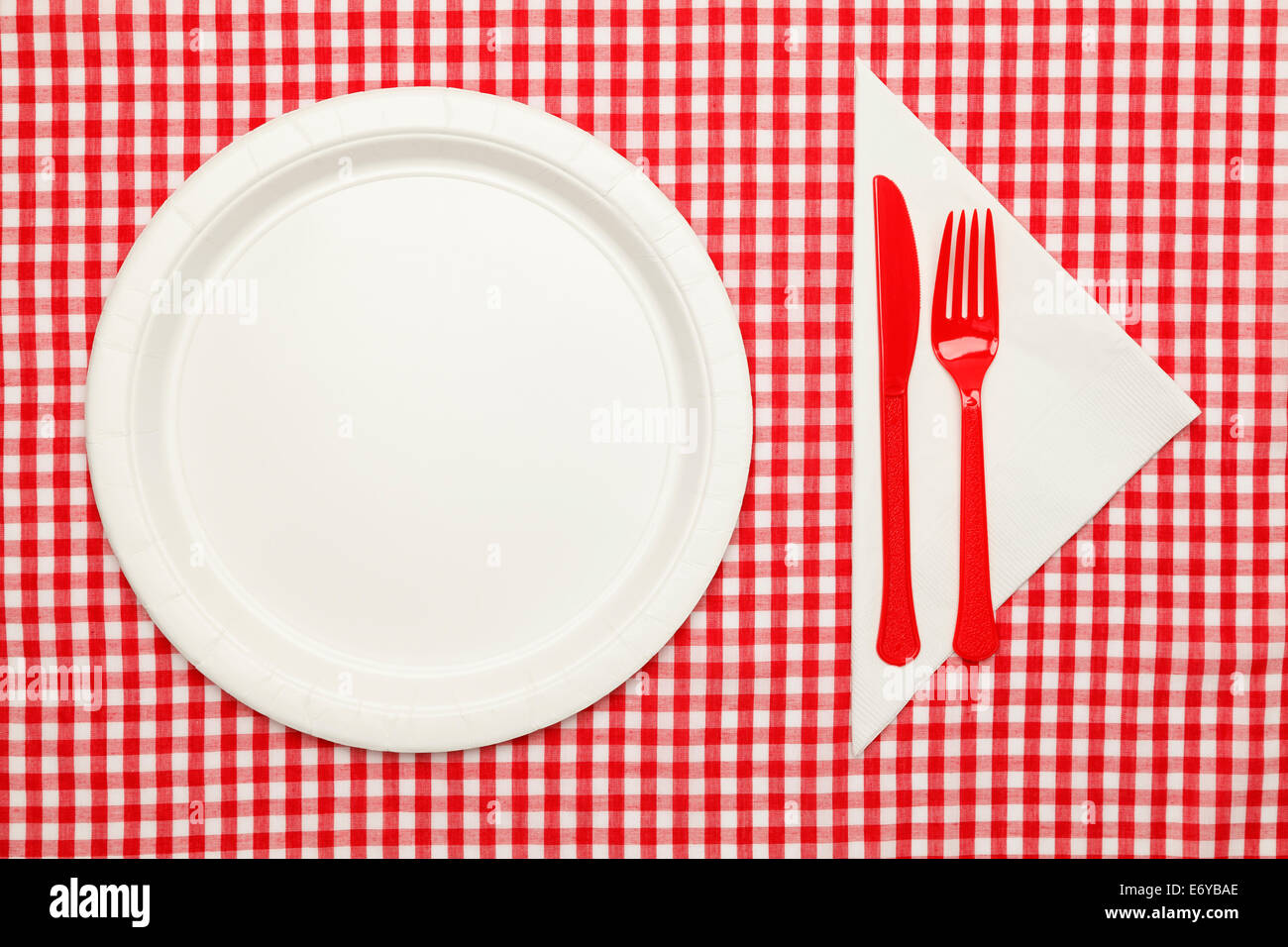Paper Plate on Checkered Table Cloth wtih Plastic Utnesils and Napkin. Stock Photo