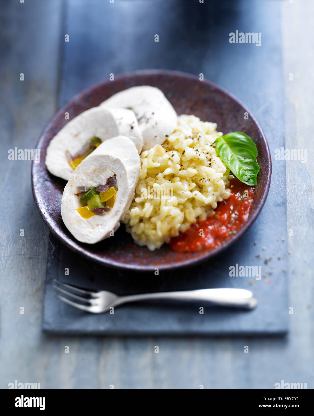 Rolled chicken breasts stuffed with peppers,risotto and tomato and pepper sauce Stock Photo