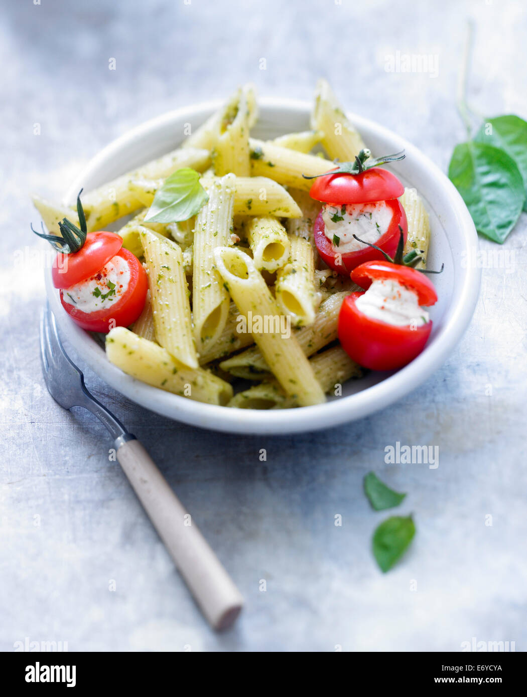 Penne with pesto and cherry tomatoes stuffed with ricotta Stock Photo