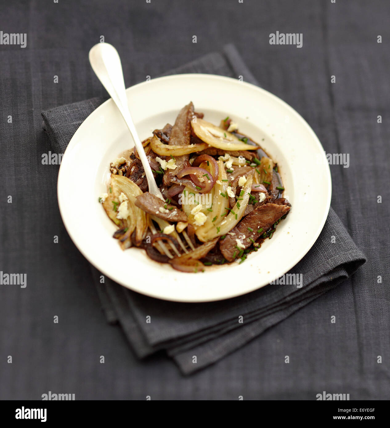 Beef,onion and fennel wok with flaked goat's cheese Stock Photo