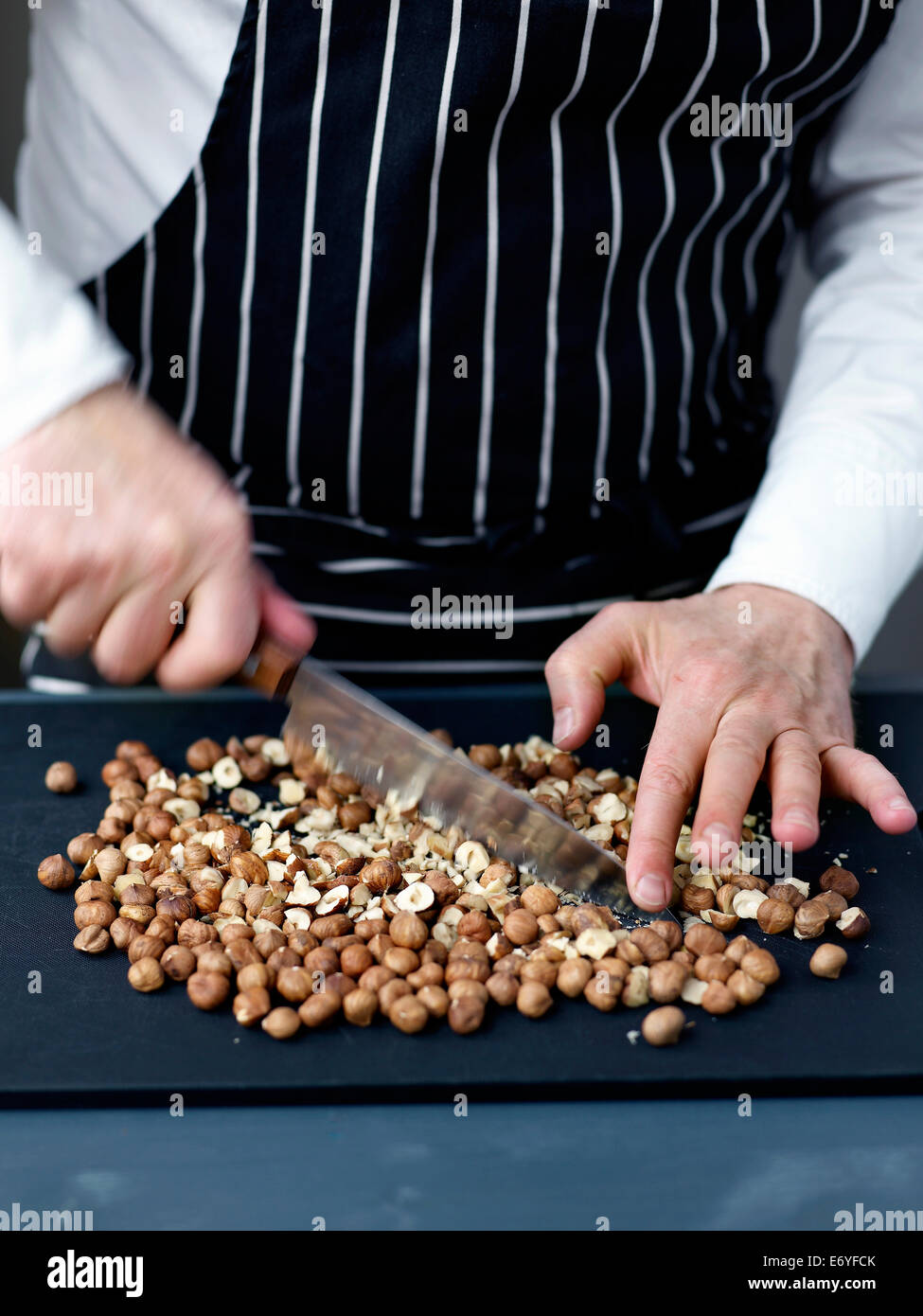 Crushing the hazelnuts with a knife Stock Photo
