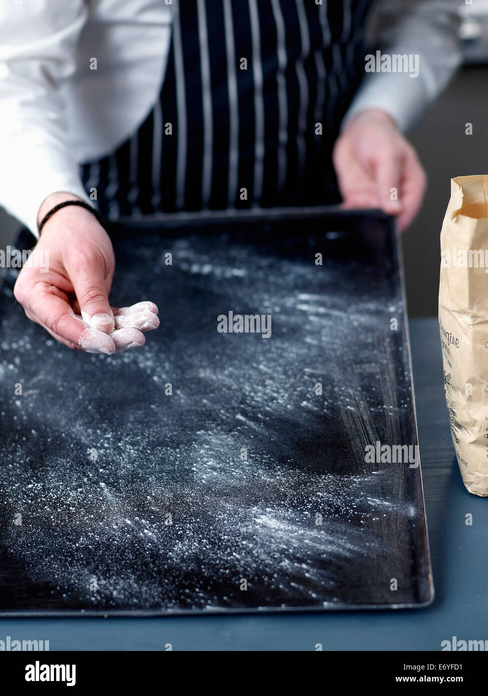 Sprinkling a little flour onto the baking tray Stock Photo