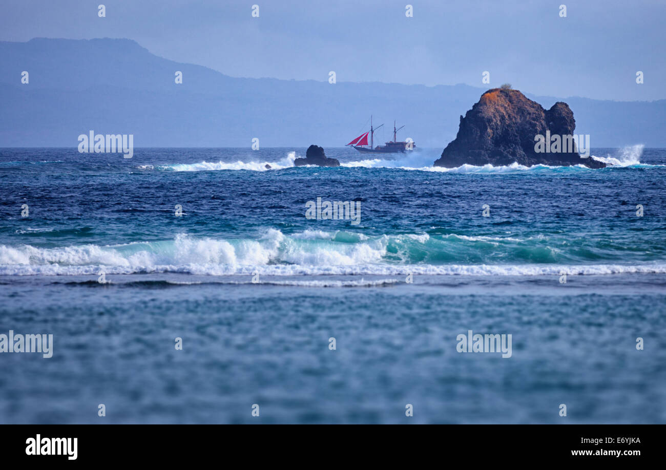 Old two-masted schooner near the rocks in the sea. Indonesia, Bali island Stock Photo