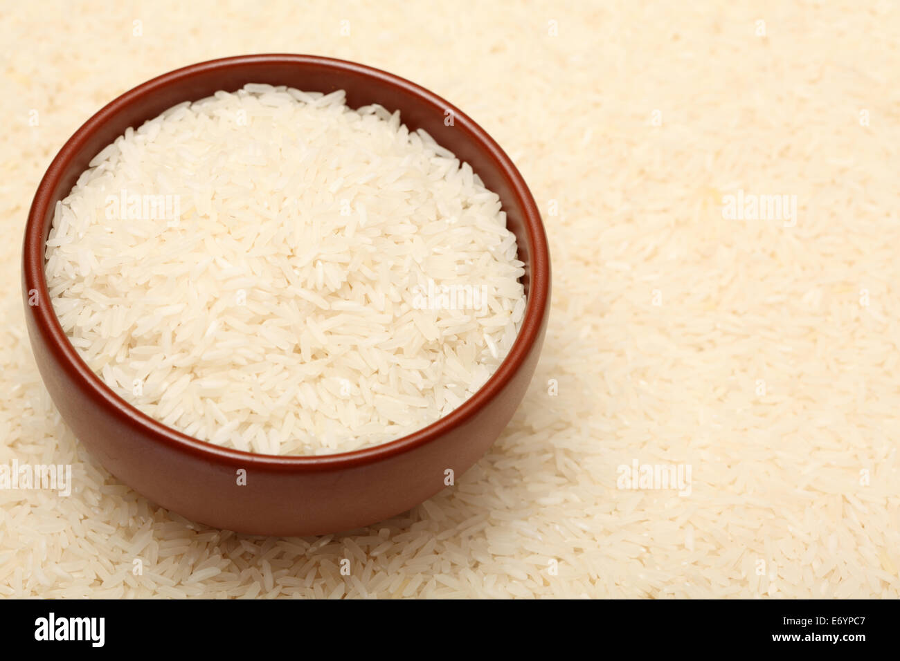 Long grain rice in bowl on rice background. Shallow depth of field. Closeup. Stock Photo