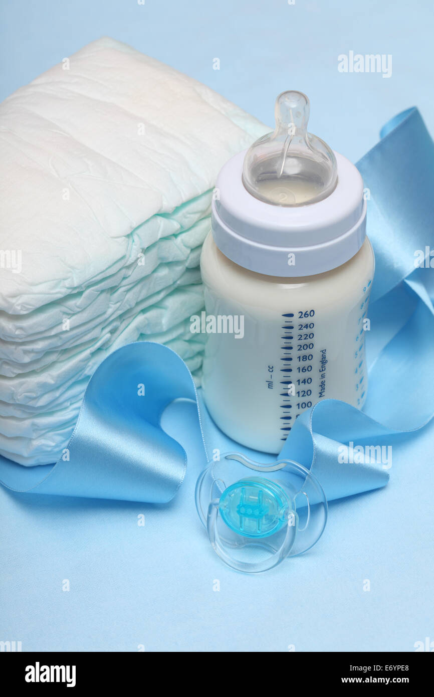 Baby bottle with milk, diapers, pacifier, and blue ribbon. Closeup