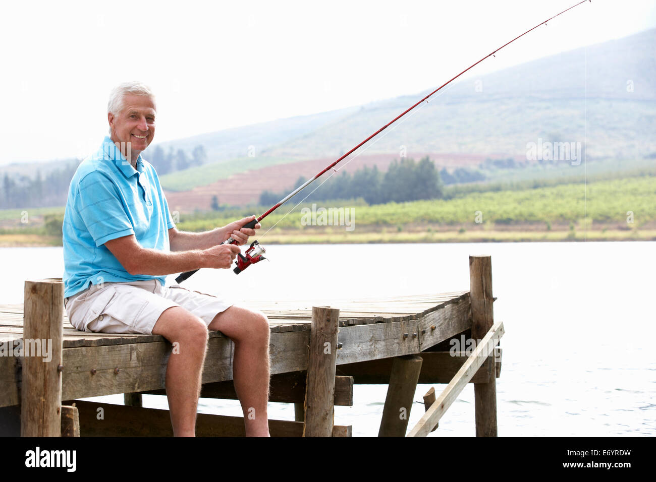 Senior man fishing on jetty Stock Photo