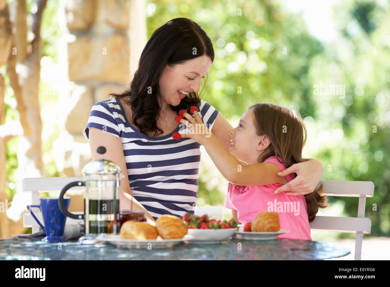 Mother and daughter eating breakfast outdoors Stock Photo