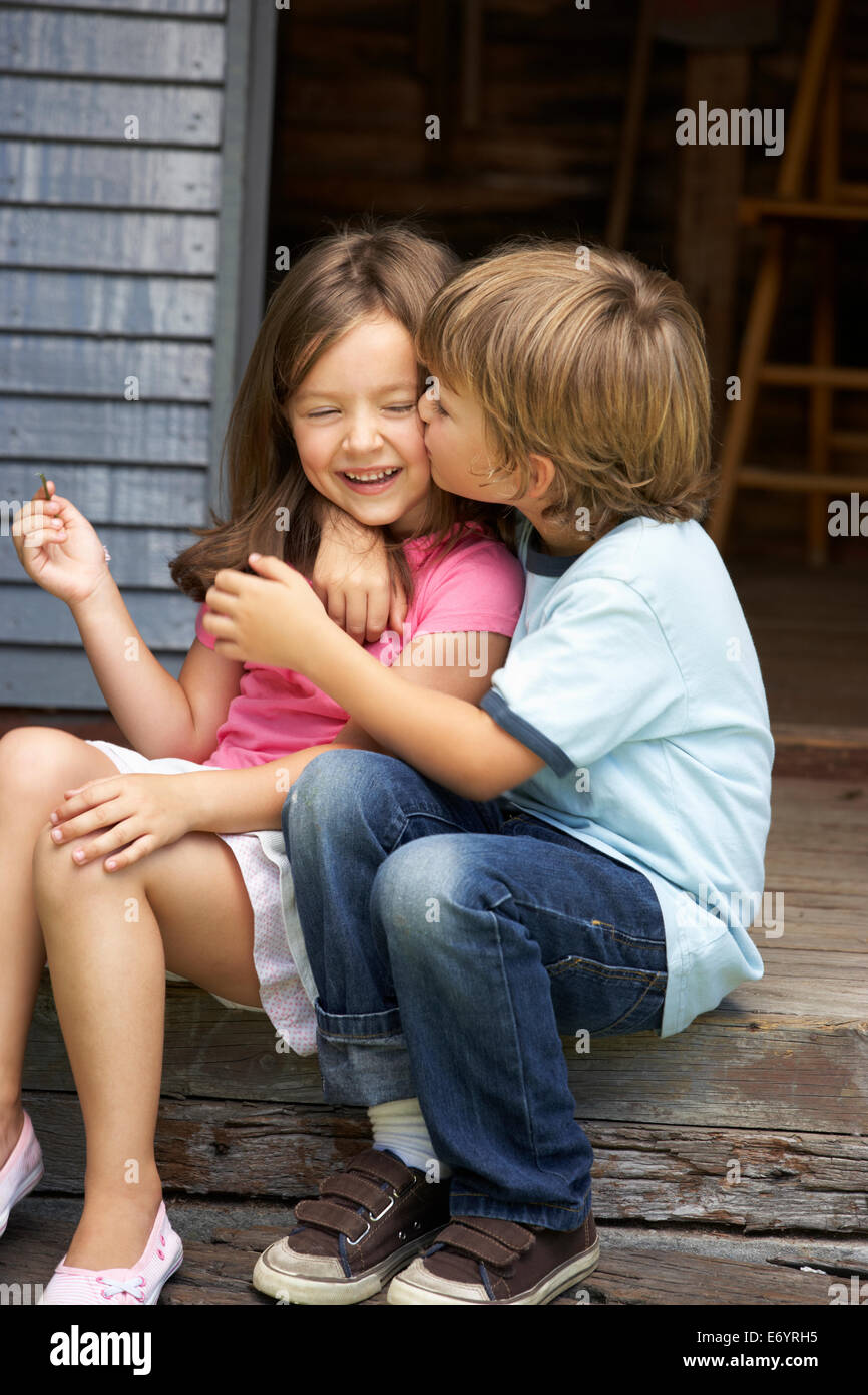 Young boy kissing sister on veranda Stock Photo