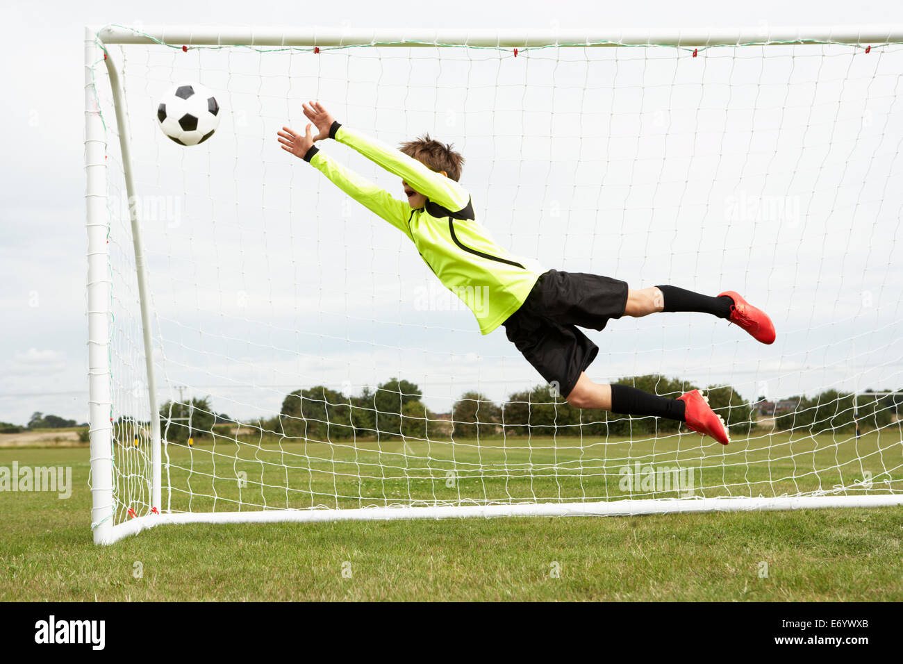 Boy goalkeeper jumping to save goal Stock Photo