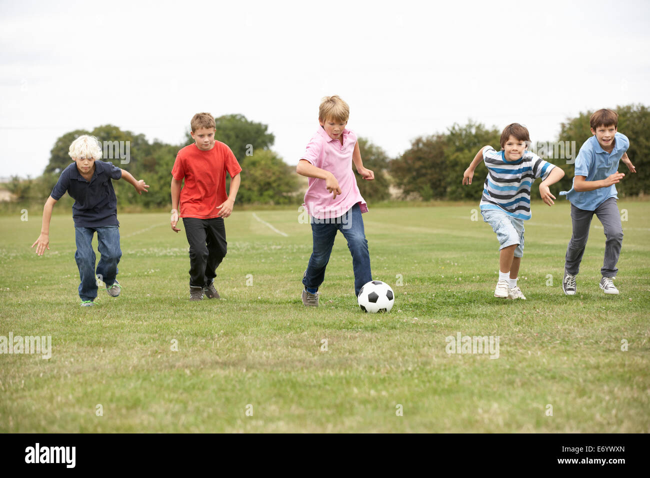 Boys playing with football in park Stock Photo