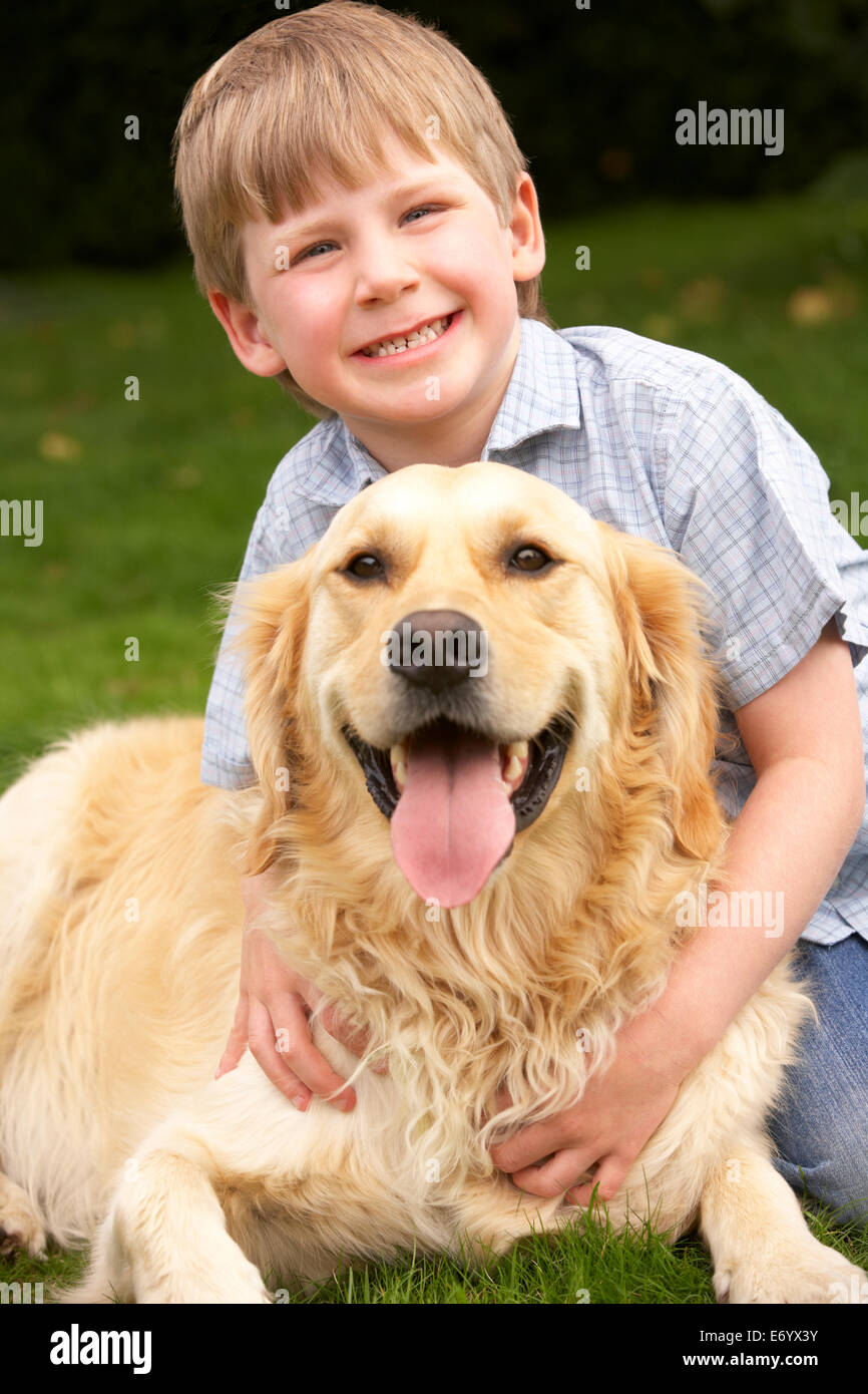 Young boy in garden with golden retriever Stock Photo
