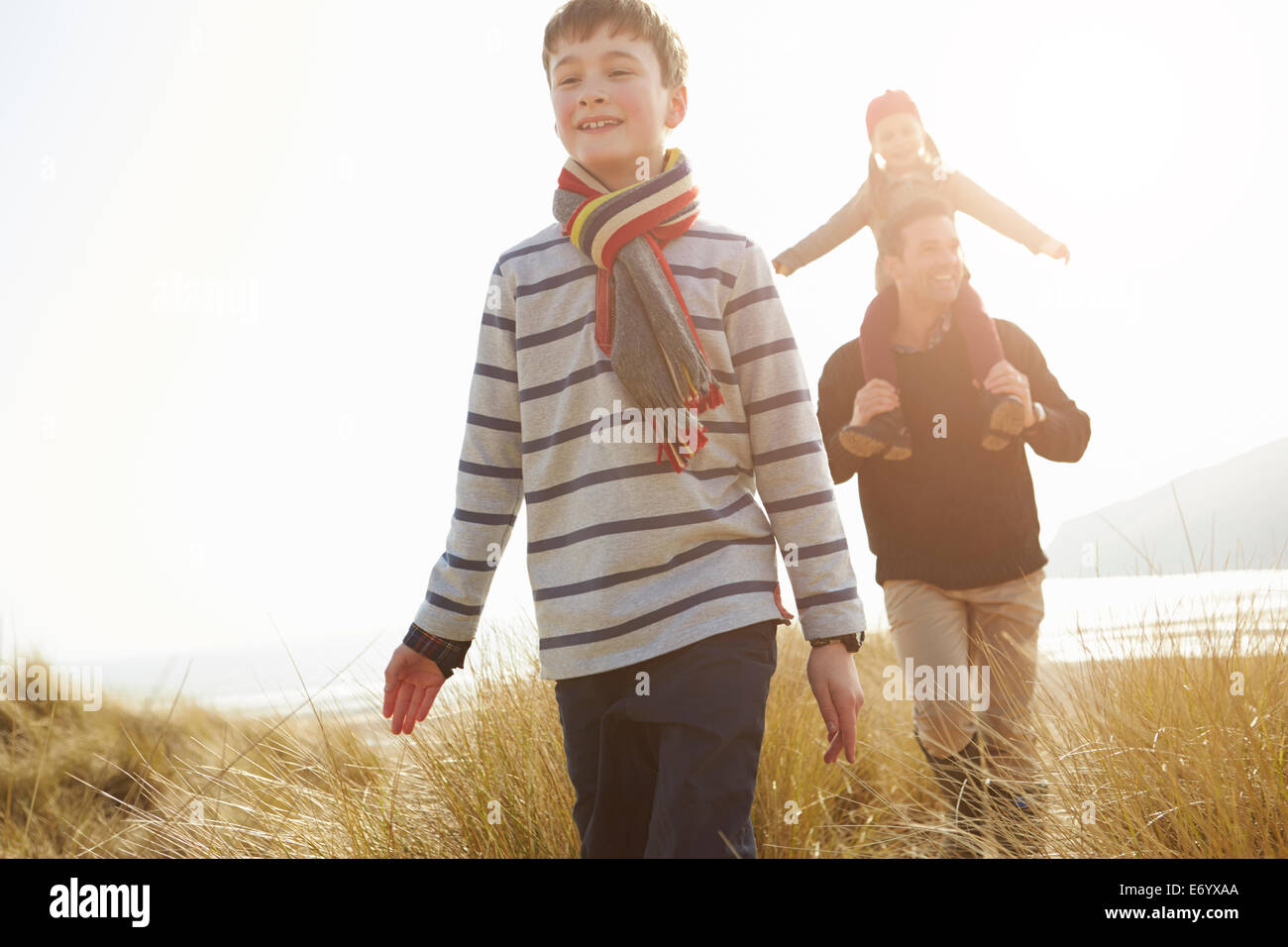 Father And Children Walking Through Dunes On Winter Beach Stock Photo