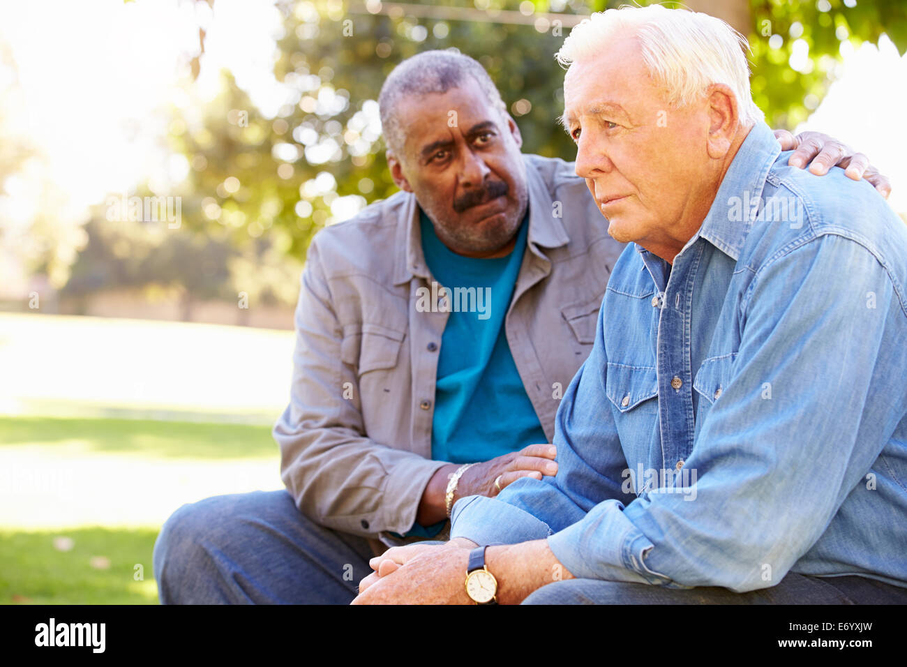 Man Comforting Unhappy Senior Friend Outdoors Stock Photo