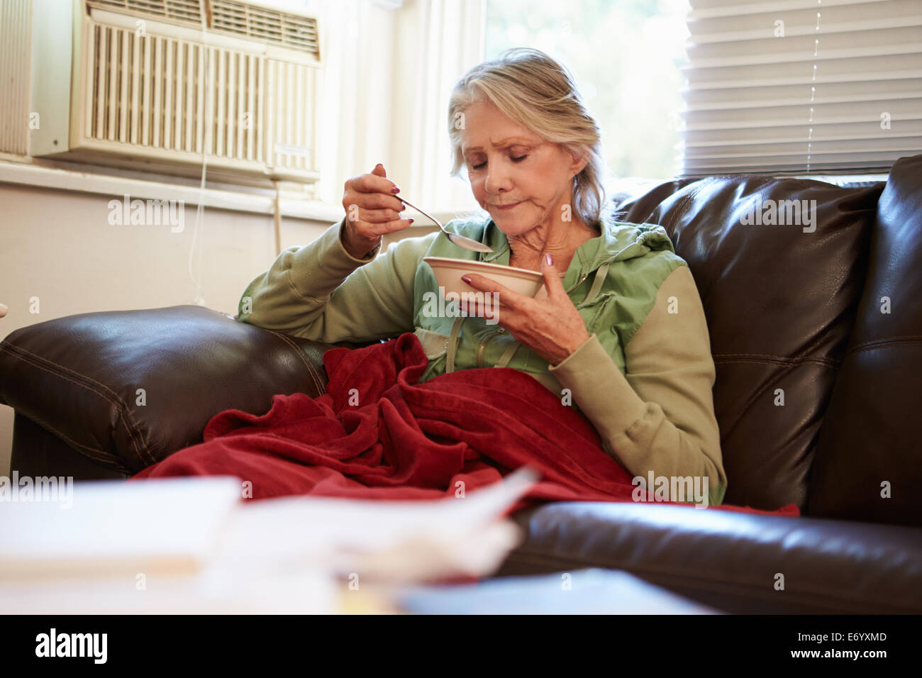 Senior Woman With Poor Diet Keeping Warm Under Blanket Stock Photo