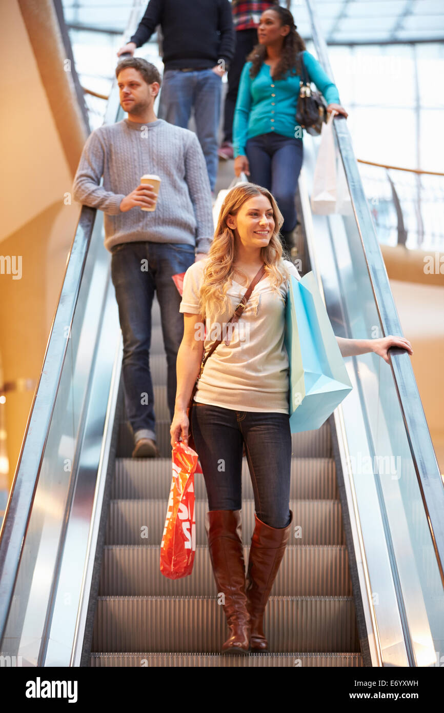Female Shopper On Escalator In Shopping Mall Stock Photo