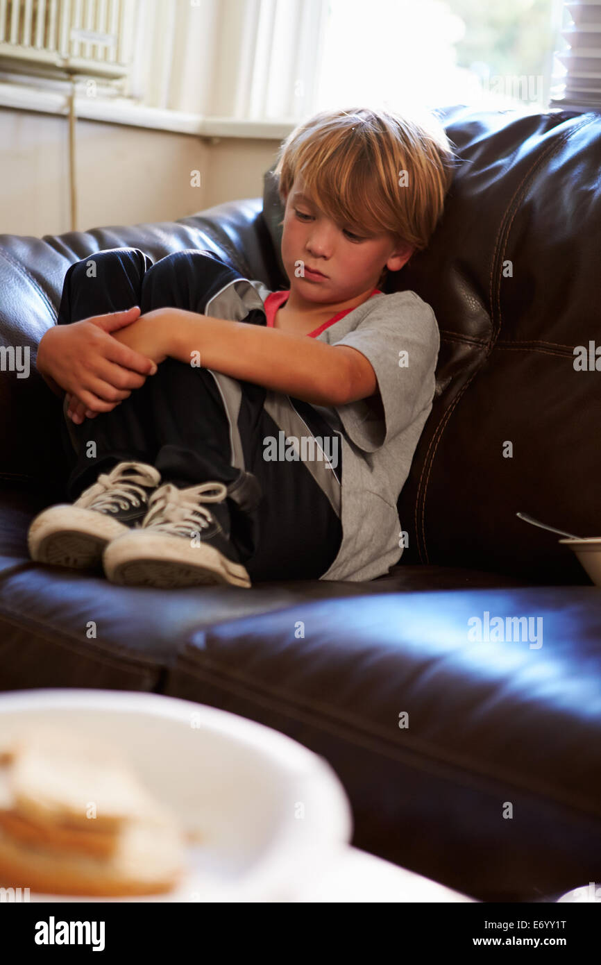 Unhappy Boy Sitting On Sofa At Home Stock Photo