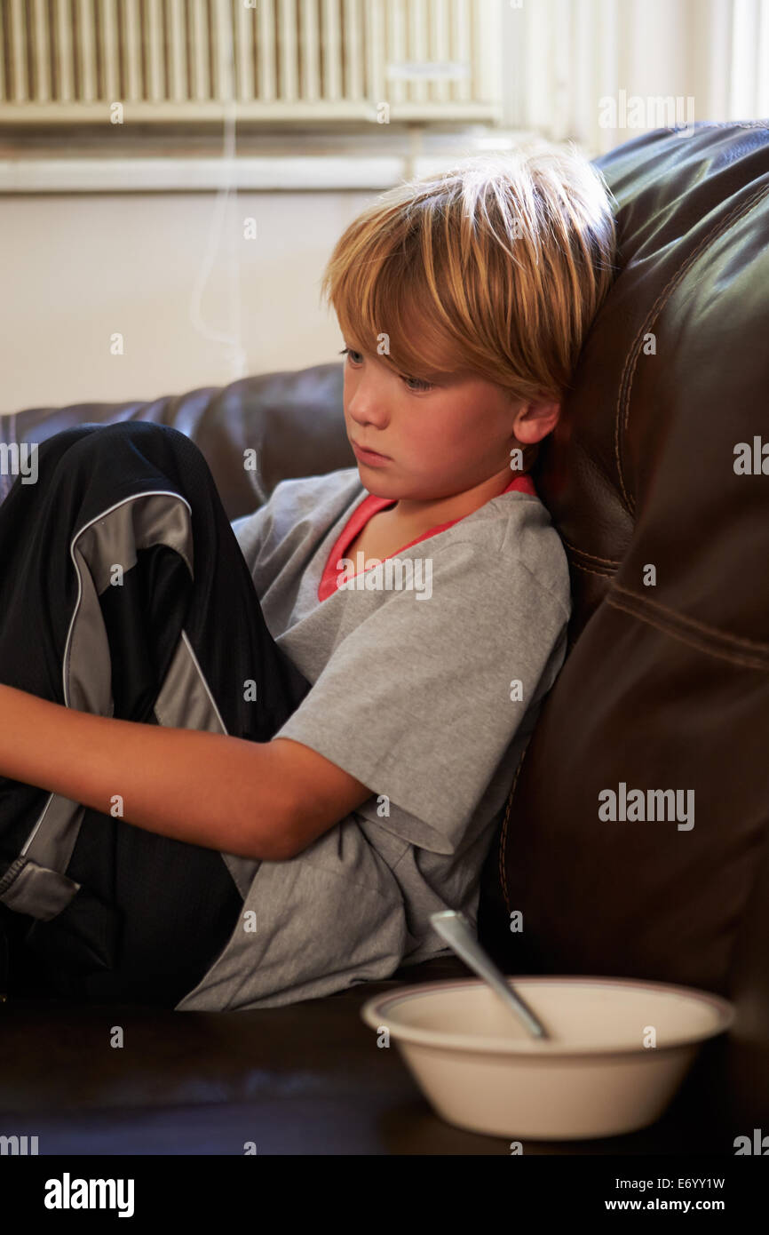 Unhappy Boy Sitting On Sofa At Home Stock Photo - Alamy