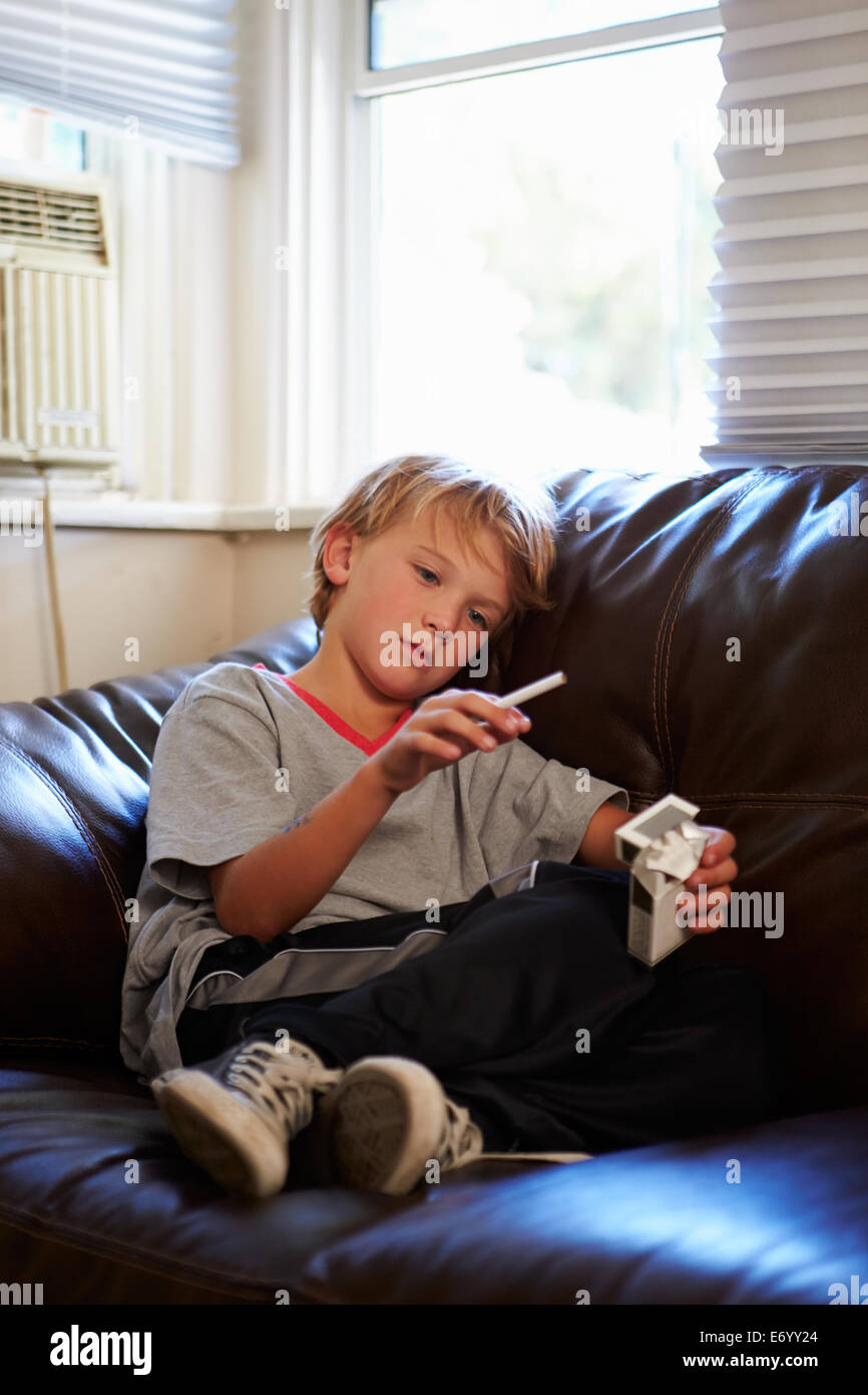 Boy Discovering Parent's Pack Of Cigarettes At Home Stock Photo