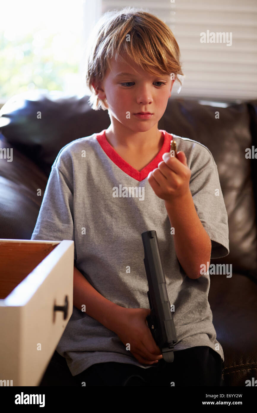 Boy Playing With Parent's Gun He Has Found At Home Stock Photo