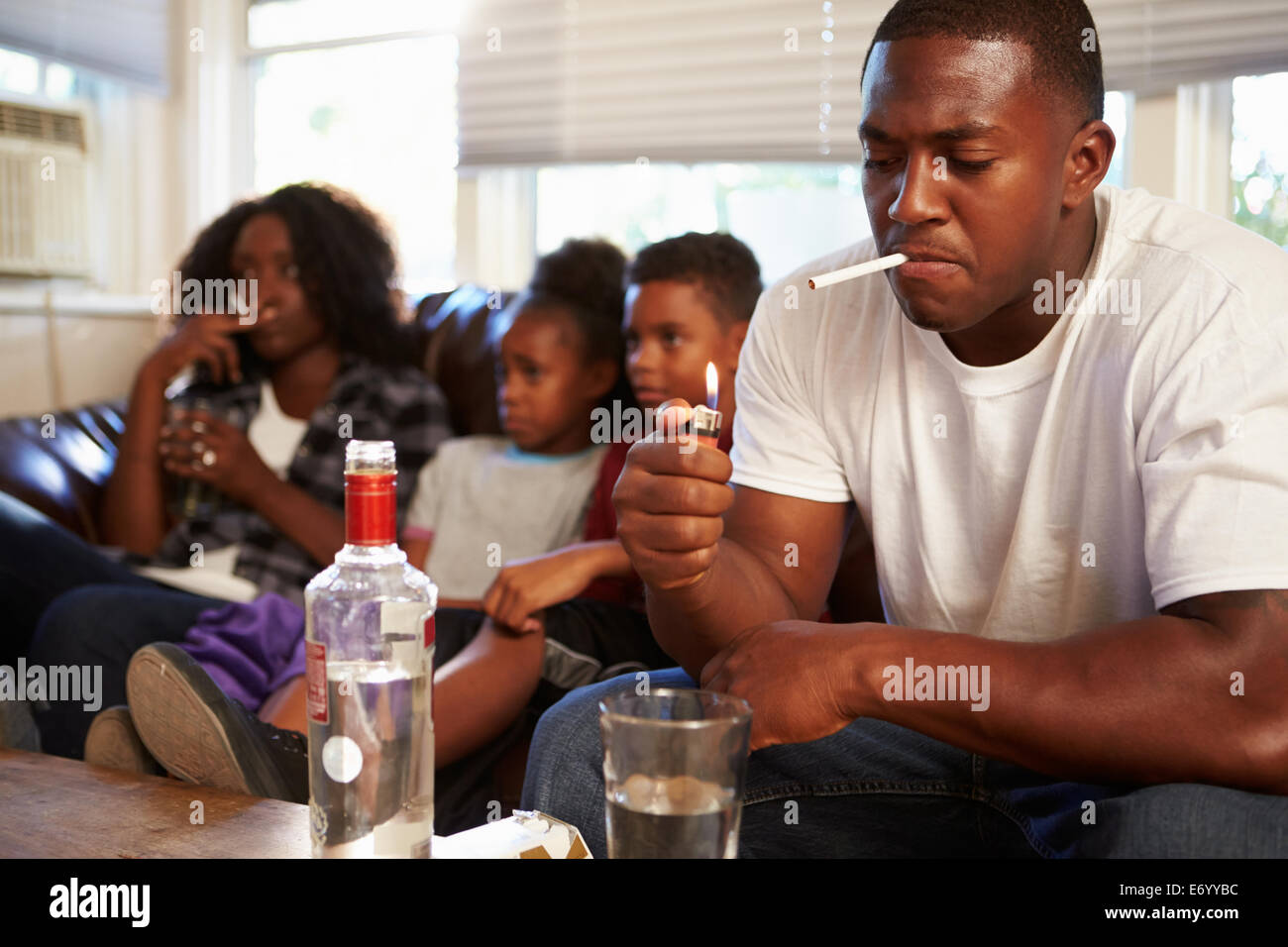 Parents Sit On Sofa With Children Smoking And Drinking Stock Photo