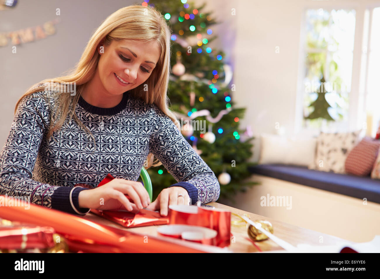 Woman Wrapping Christmas Gifts At Home Stock Photo