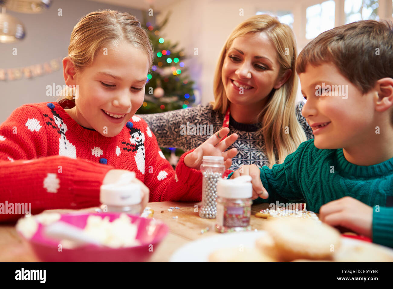 Mother And Children Decorating Christmas Cookies Together Stock Photo