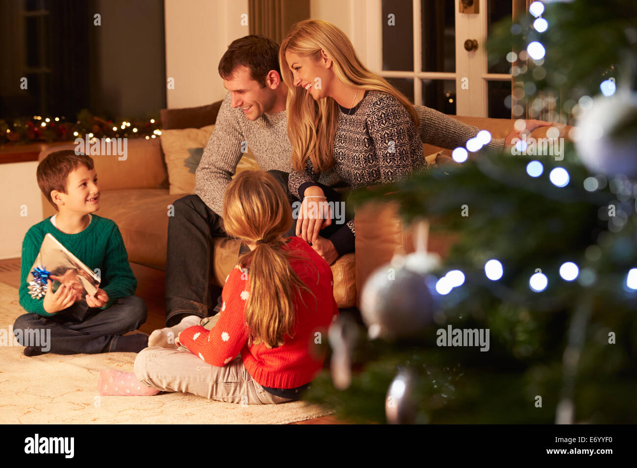 Family Exchanging Gifts By Christmas Tree Stock Photo