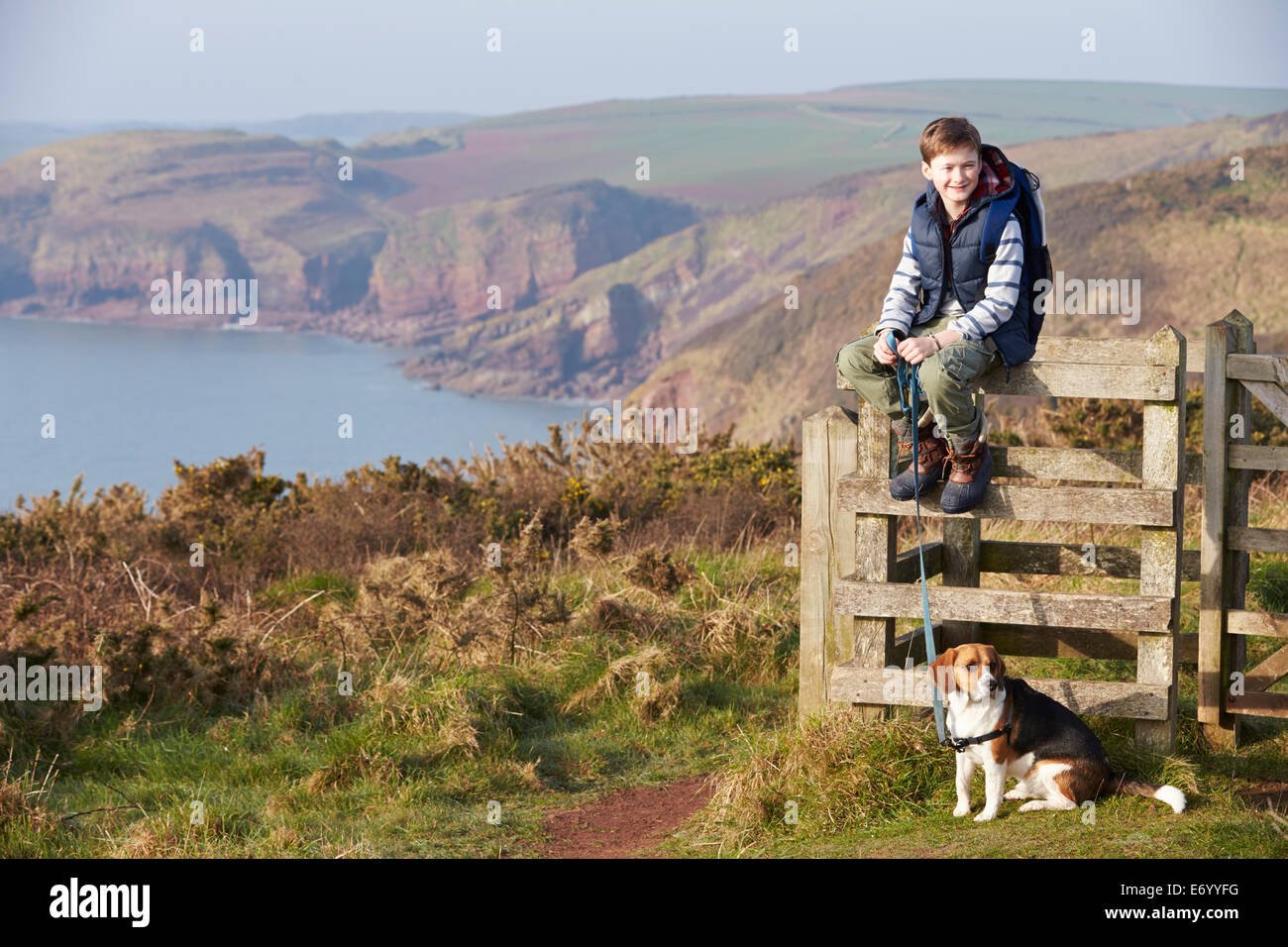 Boy With Dog Walking Along Coastal Path Stock Photo