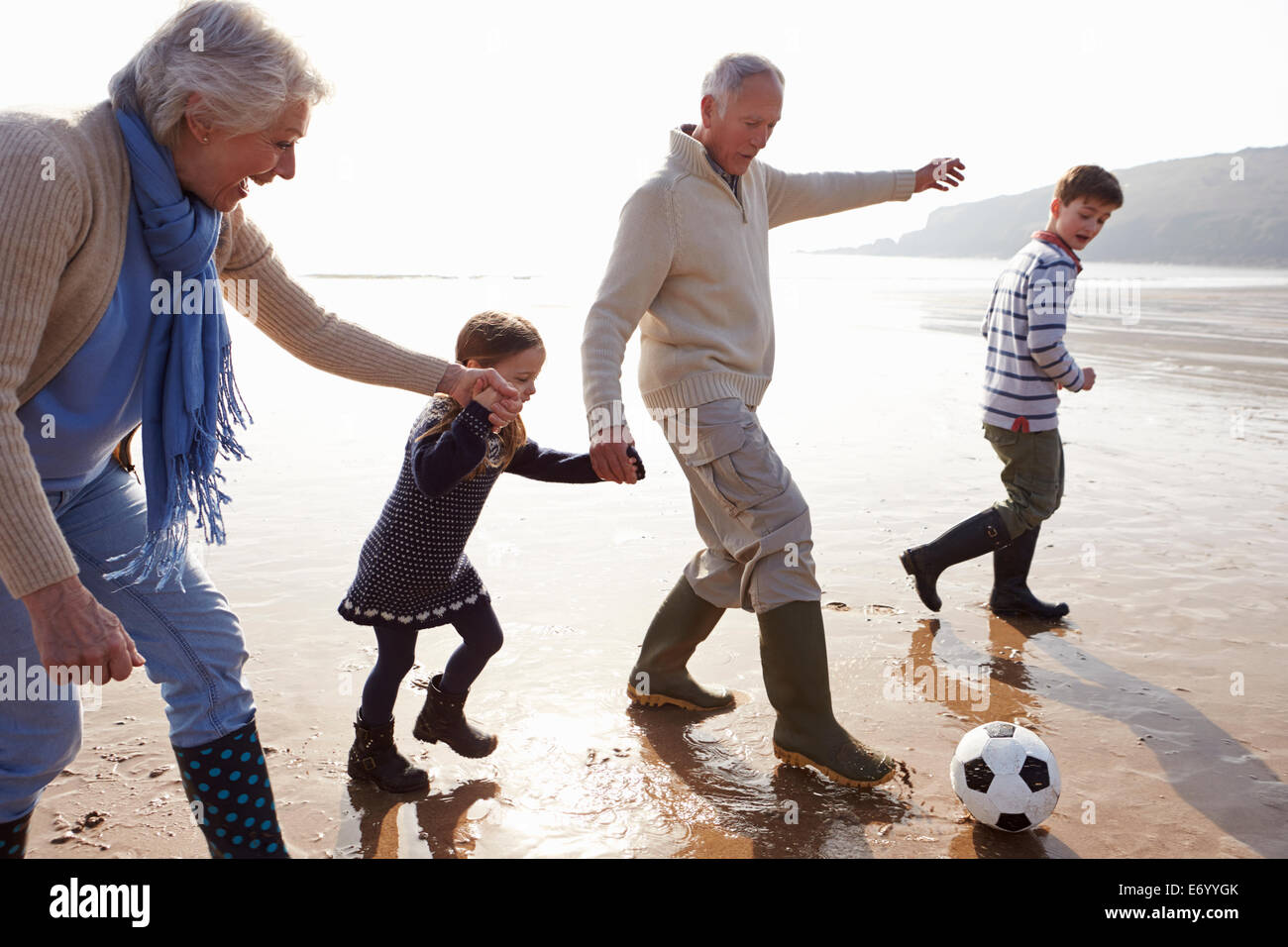 Grandparents With Grandchildren Playing Football On Beach Stock Photo