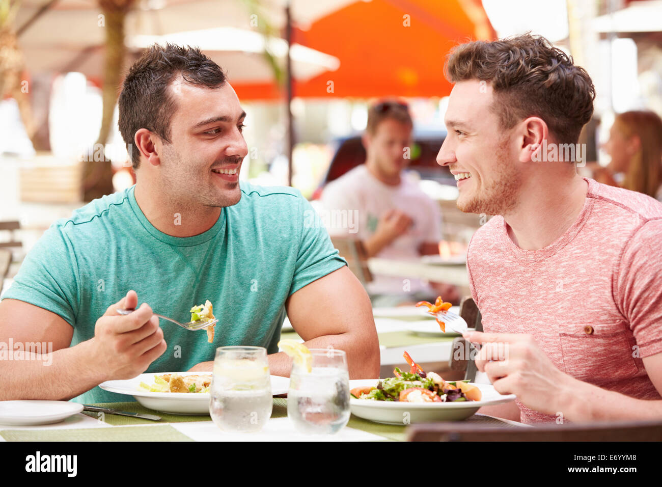 Male Couple Enjoying Lunch In Outdoor Restaurant Stock Photo