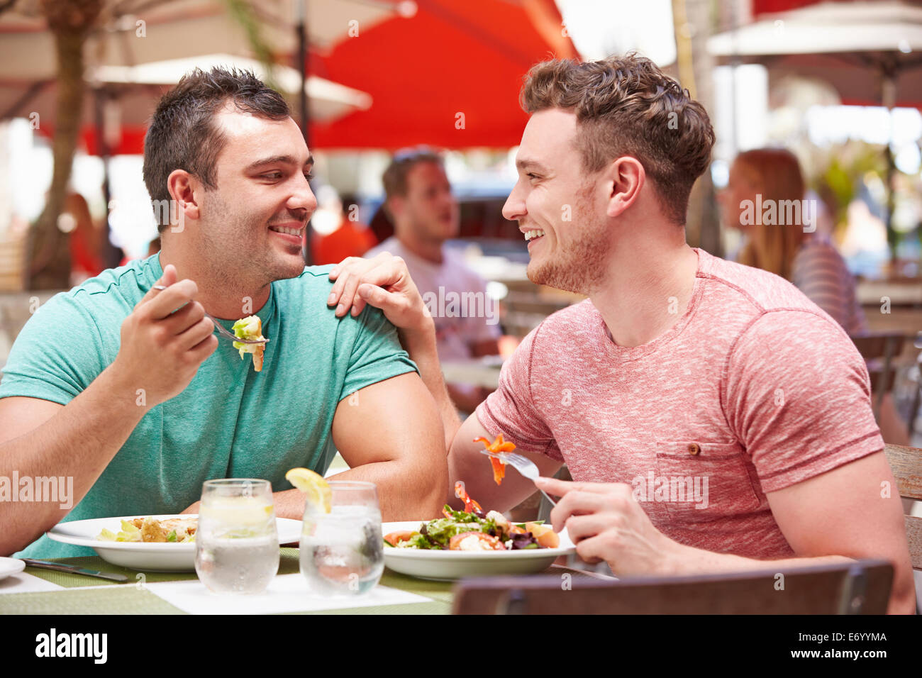 Male Couple Enjoying Lunch In Outdoor Restaurant Stock Photo