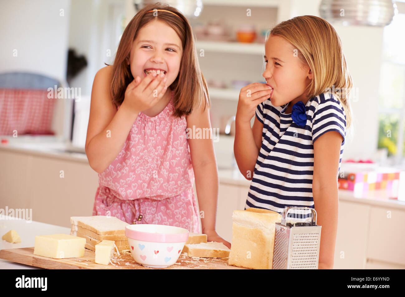 Girls Eating Ingredients Whilst Making Cheese On Toast Stock Photo