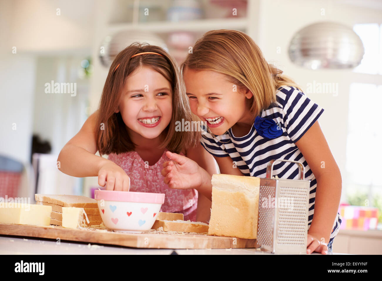 Girls Eating Ingredients Whilst Making Cheese On Toast Stock Photo