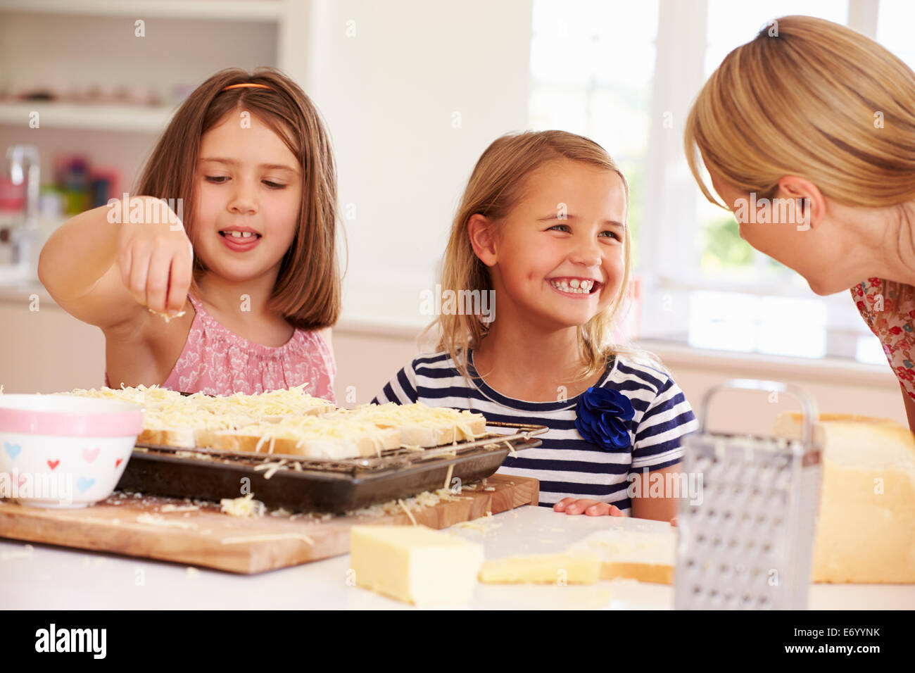 Girls With Mother Making Cheese On Toast Stock Photo
