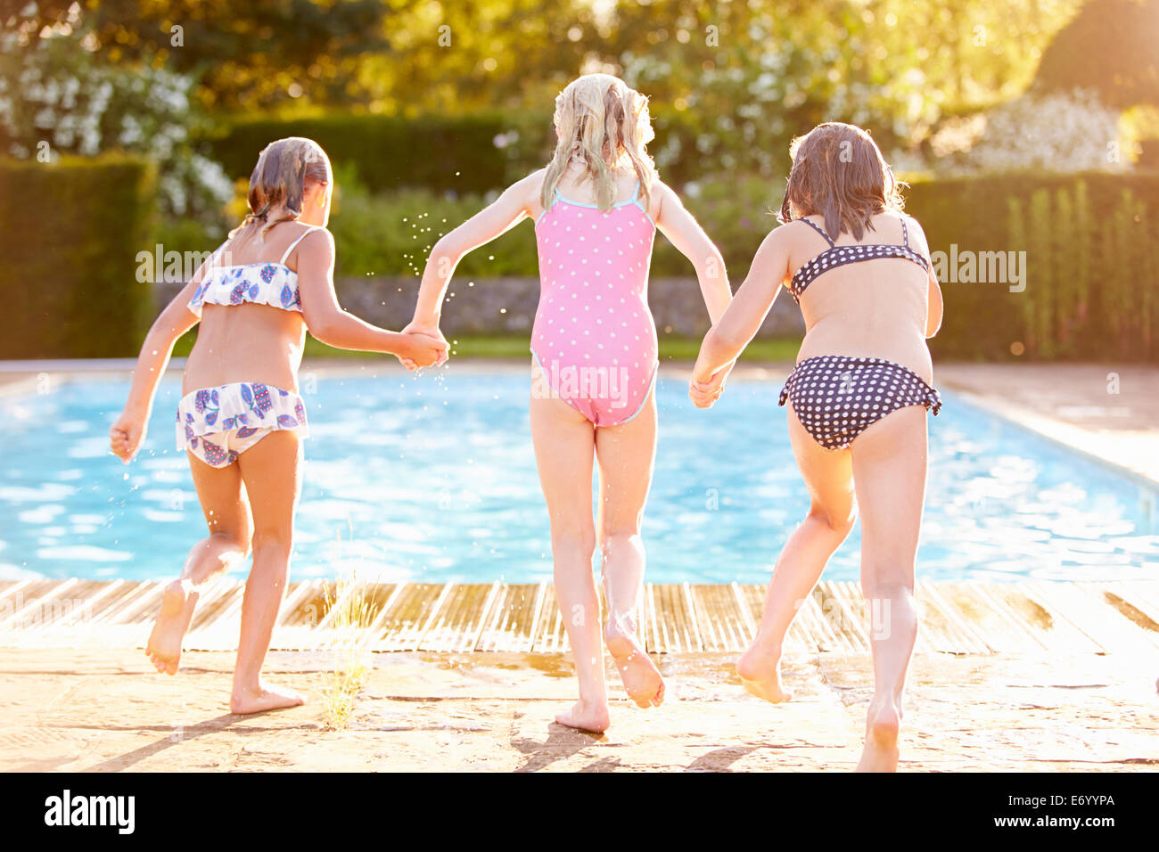 Group Of Girls Jumping Into Outdoor Swimming Pool Stock Photo